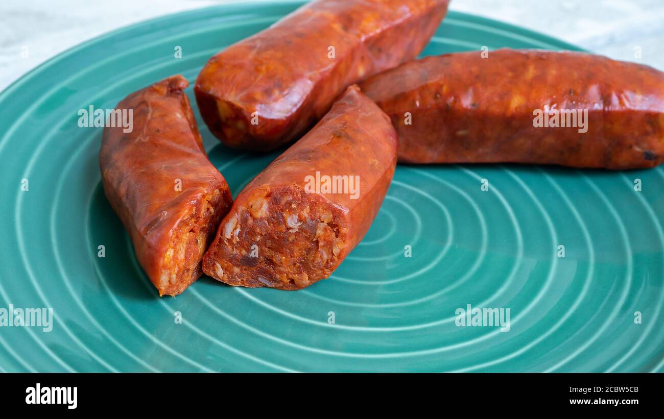 Würzige Chorizo-Wurst aufgeschnitten und auf einer grünen Platte ausgestellt. Kann als würziges Food-Konzept Foto verwendet werden. Stockfoto