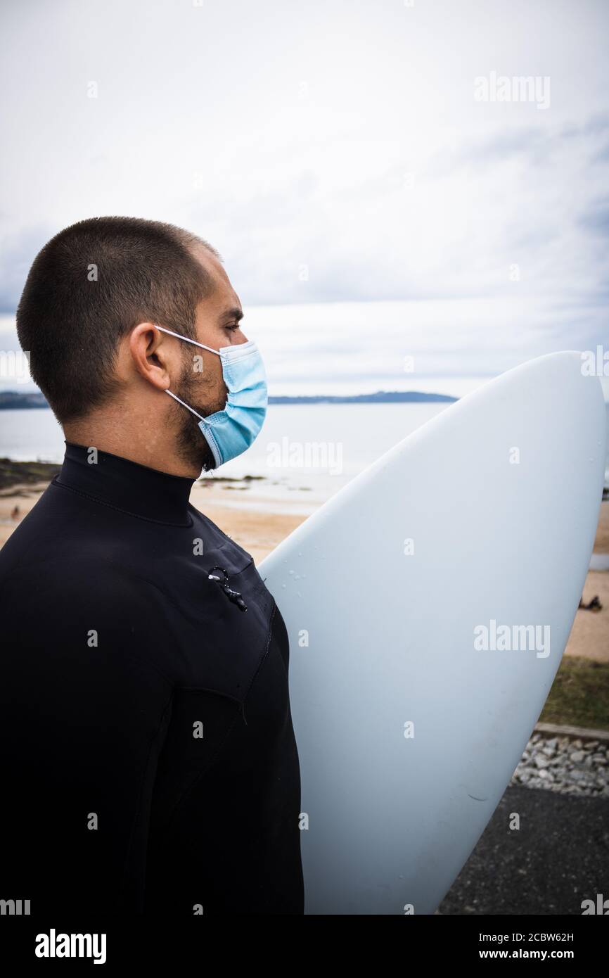 Surfbrett Surfer, Mann in Maske und Wetsuit am Strand Stockfoto