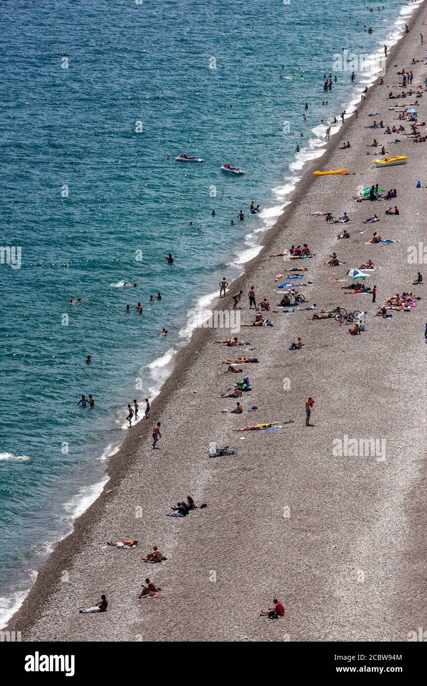 Badende reax am Strand von Konyaalti Plaji in Antalya in der Türkei. Auf der linken Seite befindet sich die Bucht von Antalya, die Teil des Mittelmeers ist. Stockfoto