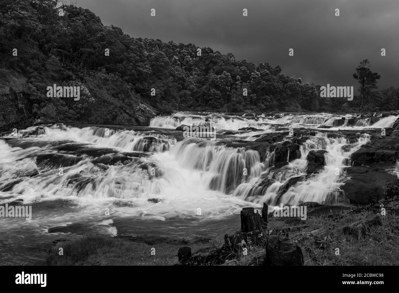 Wasserfall mit roten Felsen und grünen üppigen Wald flachen Winkel in schwarz und weiß Bild geschossen wird am Pykara See ooty tamilnadu südindien genommen. Es ist showi Stockfoto