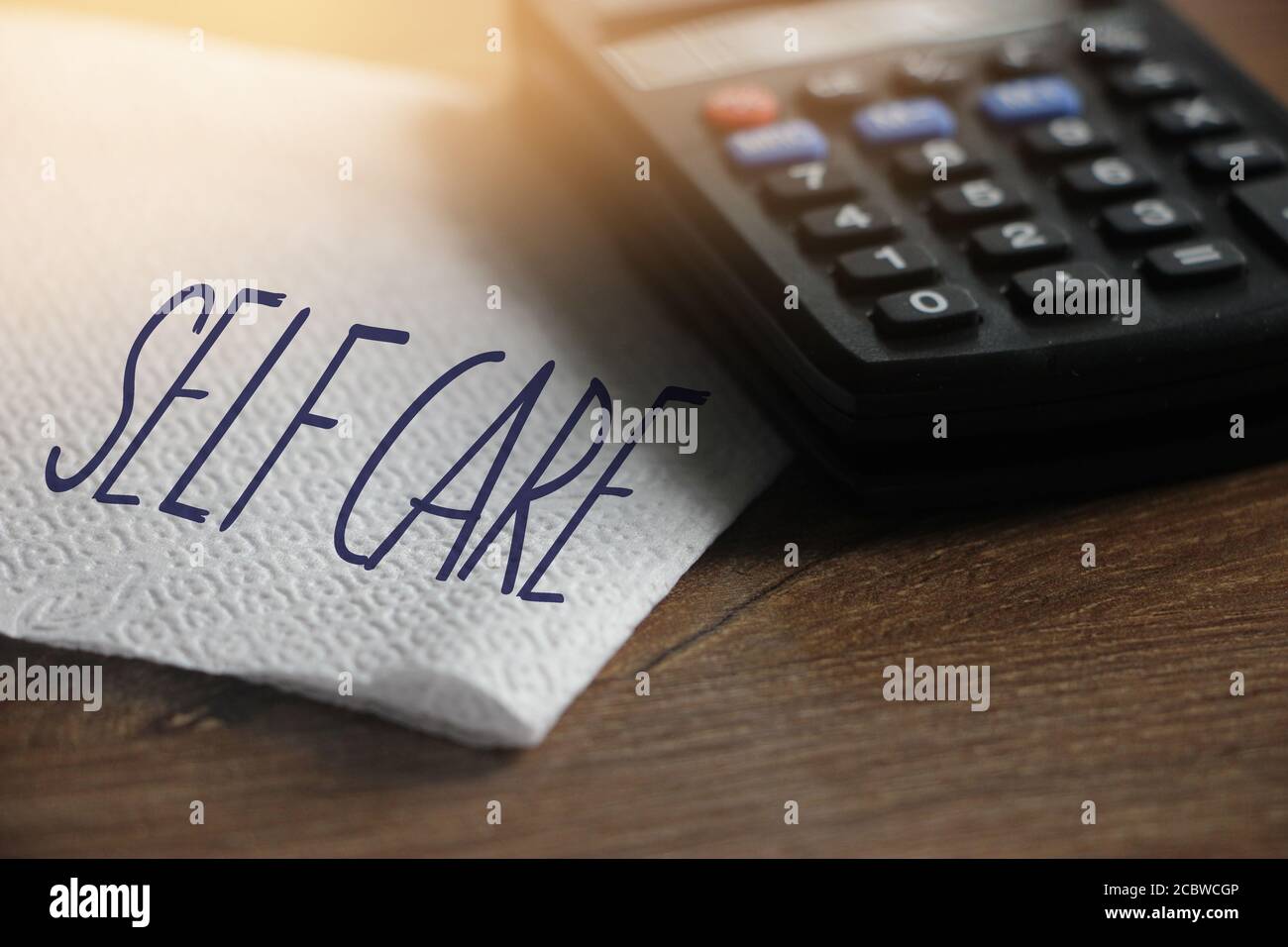 Selbstpflege Worte auf Serviette und Taschenrechner auf Holztisch. Gesundheitskonzept Stockfoto