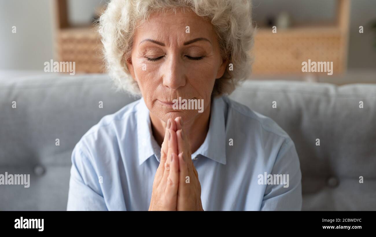 Achtsame ältere Frau betet Gott mit geschlossenen Augen. Stockfoto
