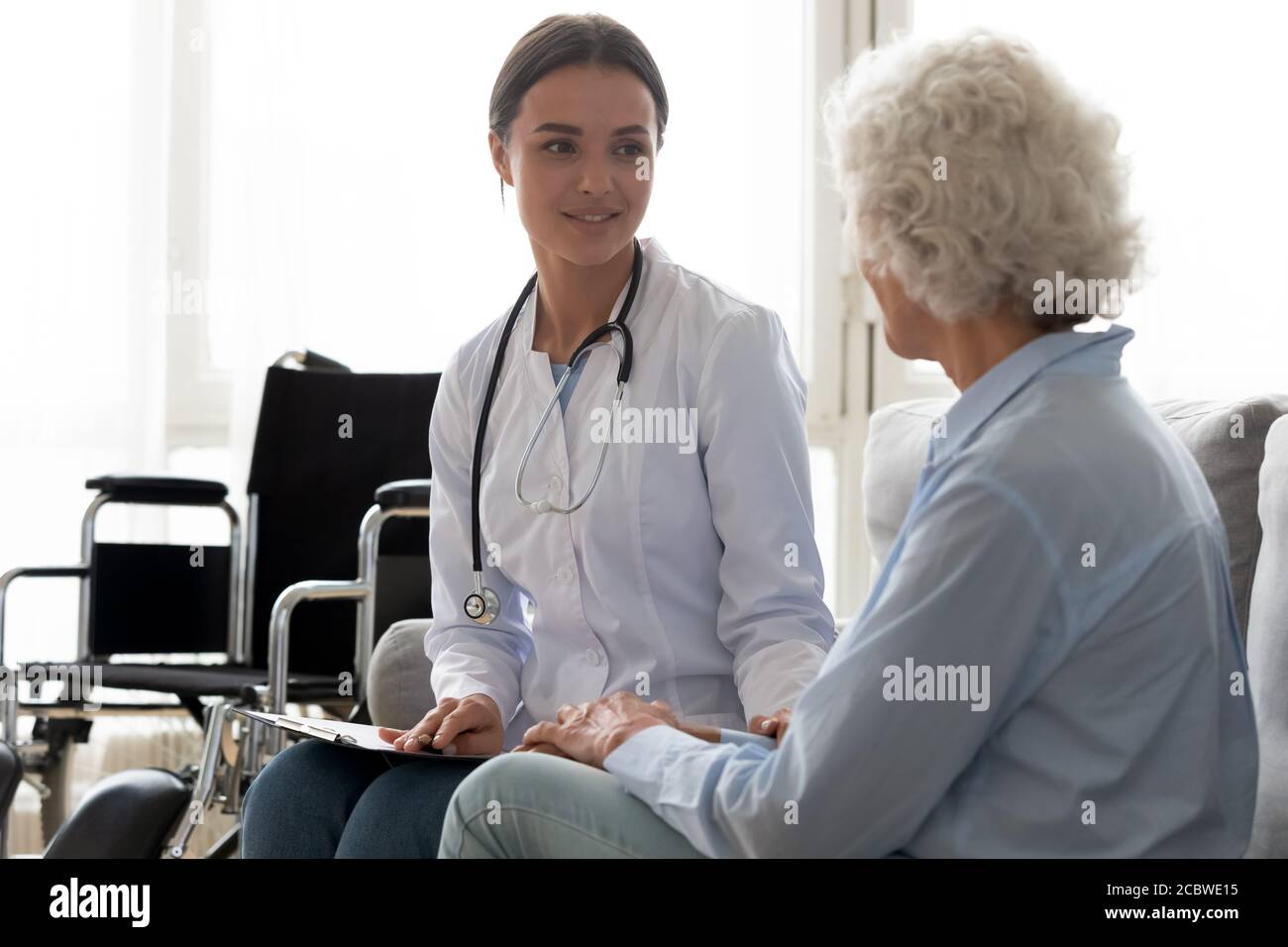 Junge Ärztin besucht behinderte ältere ältere ältere Patienten. Stockfoto