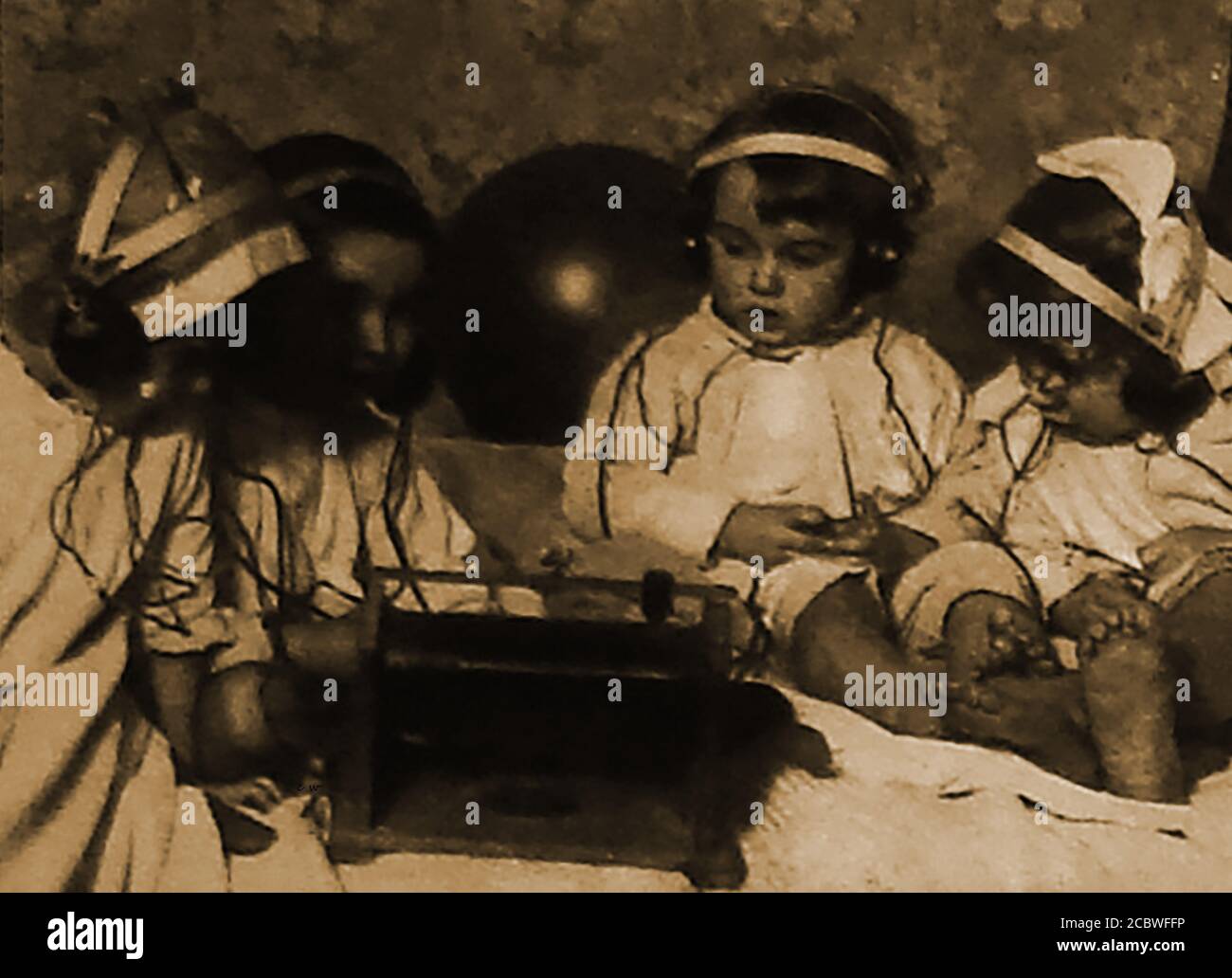1922 faszinierte Kleinkinder sitzen und hören einem der Neueren zu Radios mit Kopfhörern erfunden Stockfoto