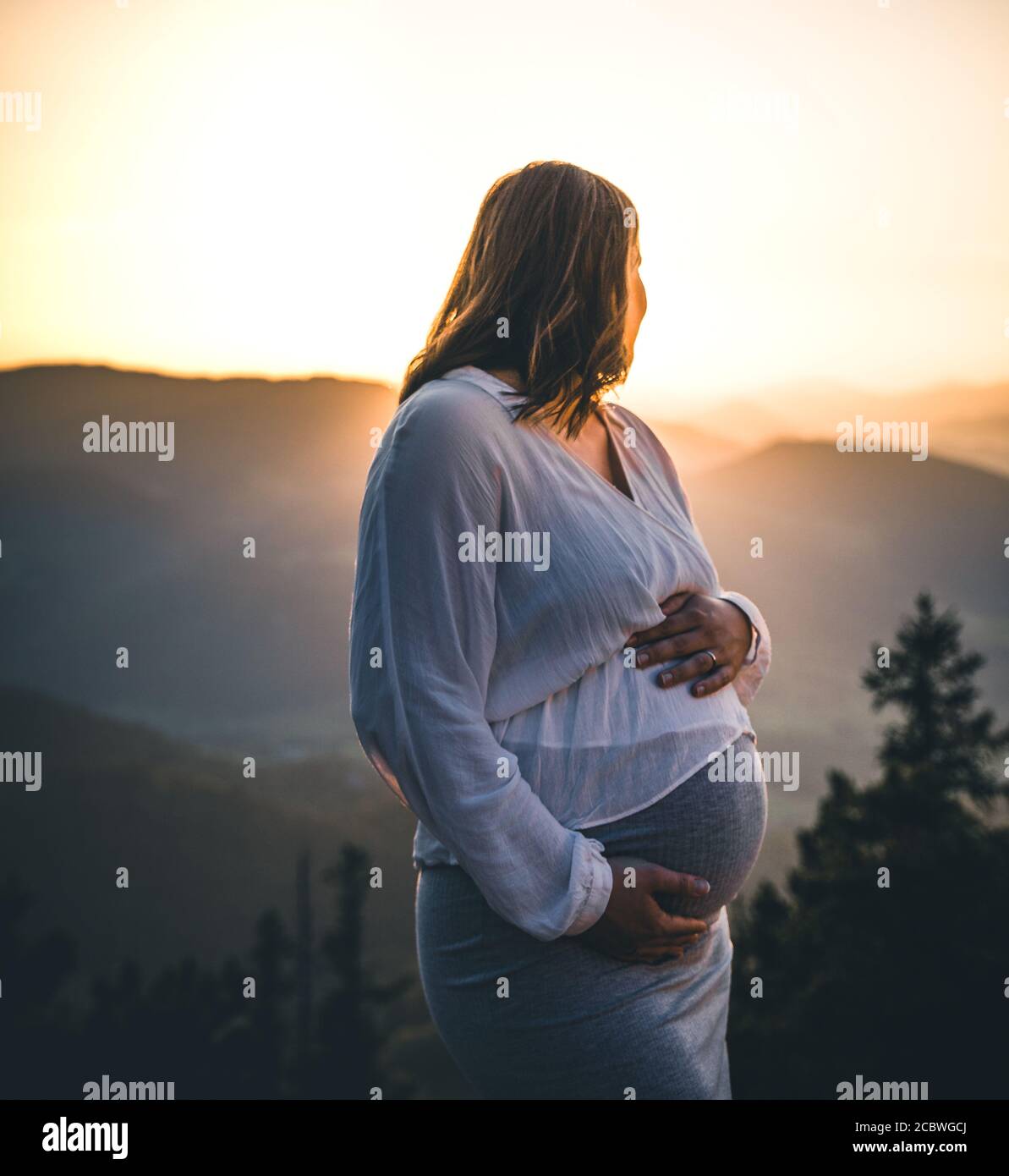 Schwangere Frau Sonnenuntergang Silhouette auf einem Hochhaus in österreich Stockfoto