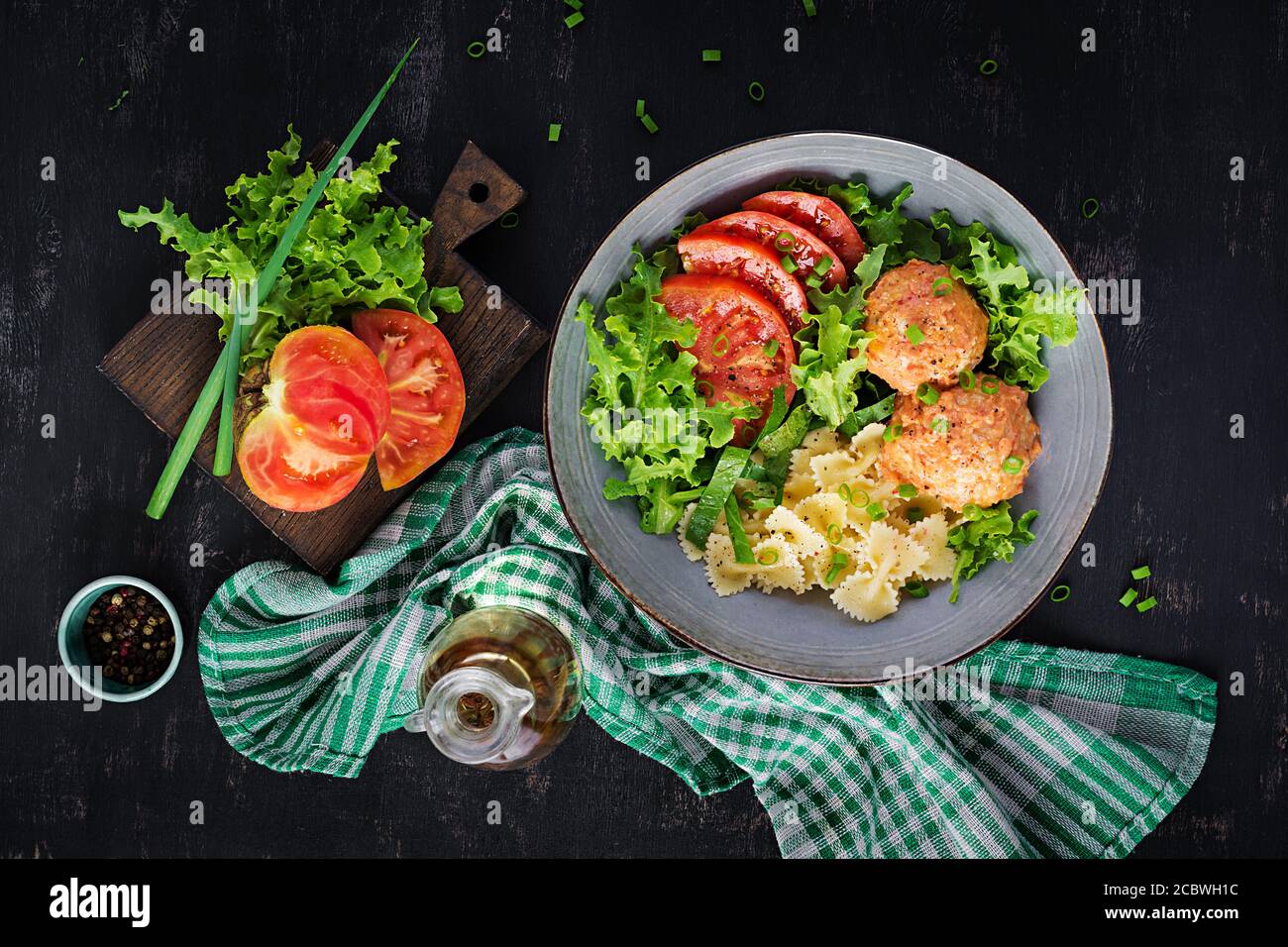 Italienische Pasta. Farfalle mit Fleischbällchen und Salat auf dunklem Hintergrund. Abendessen. Draufsicht, Overhead. Slow Food Konzept Stockfoto