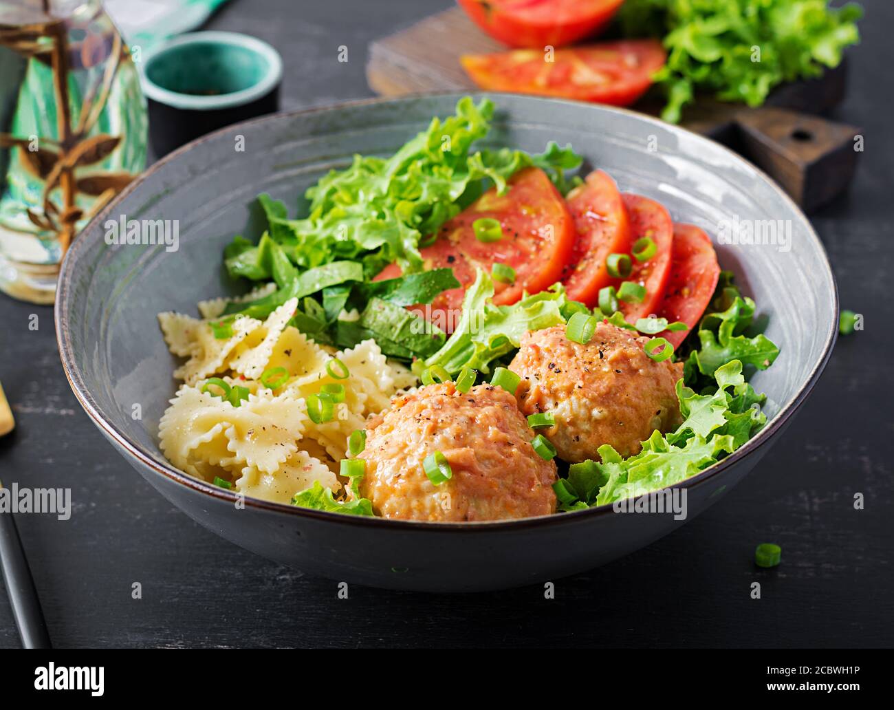 Italienische Pasta. Farfalle mit Fleischbällchen und Salat auf dunklem Hintergrund. Abendessen. Slow Food Konzept Stockfoto