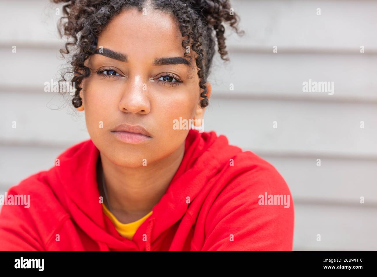 Mädchen Teenager Teenager weiblich junge afroamerikanische gemischte Rasse biracial Frau draußen sah nachdenklich und trägt roten Hoodie Stockfoto