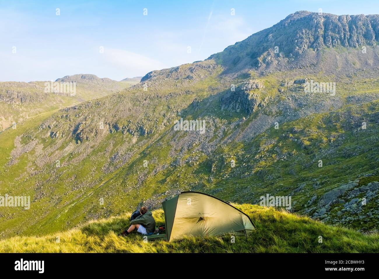 Wildes Campen auf Crinkle Crags beim Rucksackwandern in den Bergen des Lake District National Park, Großbritannien. Bowfell in der Ferne Stockfoto