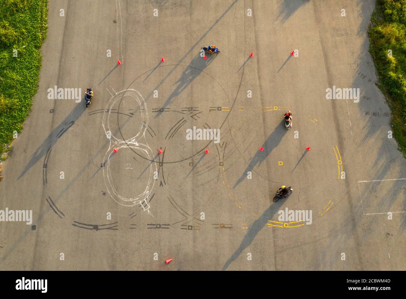 Von oben nach unten breite Luftaufnahme von vier Fahrern, die Spaß auf  einem fortgeschrittenen Motorrad-Slalom-Kurs zwischen orangen Kegeln mit  langen Schatten haben, bemalt Stockfotografie - Alamy