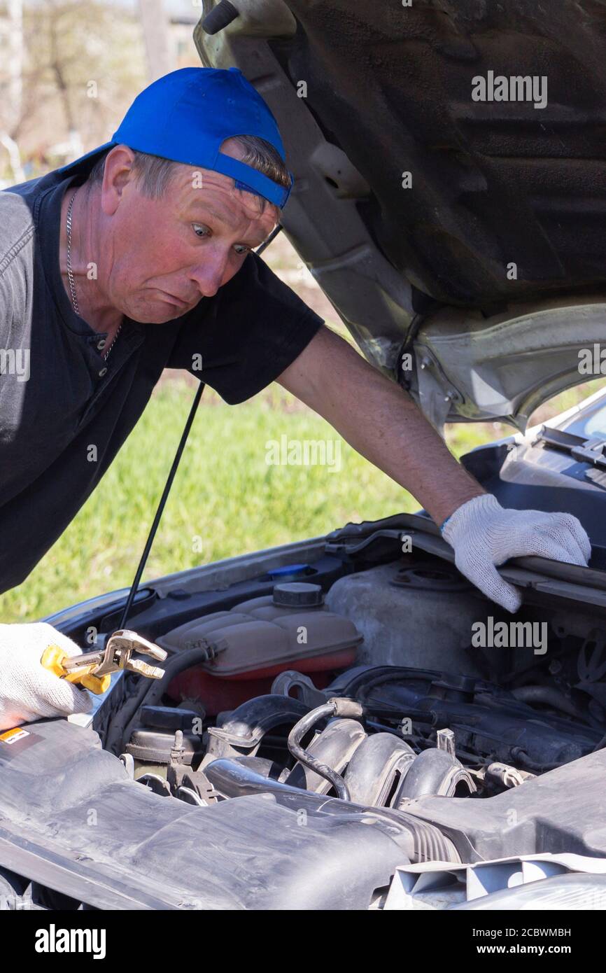 Überraschender Mechaniker schaut in das Auto. Stockfoto