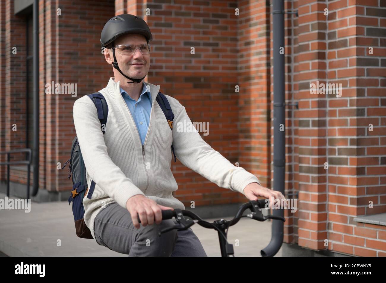 Reifer Kaukasischer Mann in einem Fahrradhelm auf seinem Fahrrad In einer Stadt Stockfoto