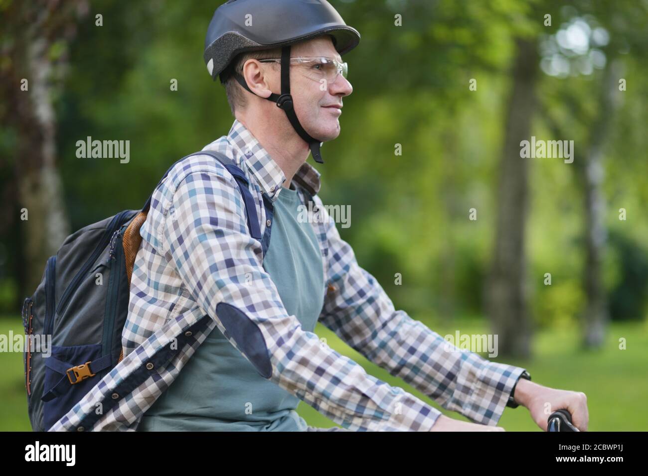 Reifer Kaukasischer Mann in einem Fahrradhelm auf seinem Fahrrad In einem Stadtpark Stockfoto