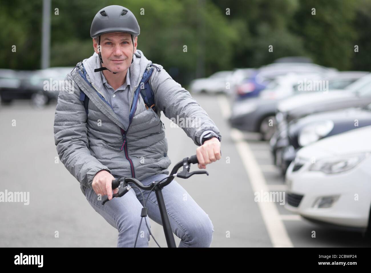 Reifer Kaukasischer Mann in einem Fahrradhelm auf seinem Fahrrad Auf einem Parkplatz Stockfoto