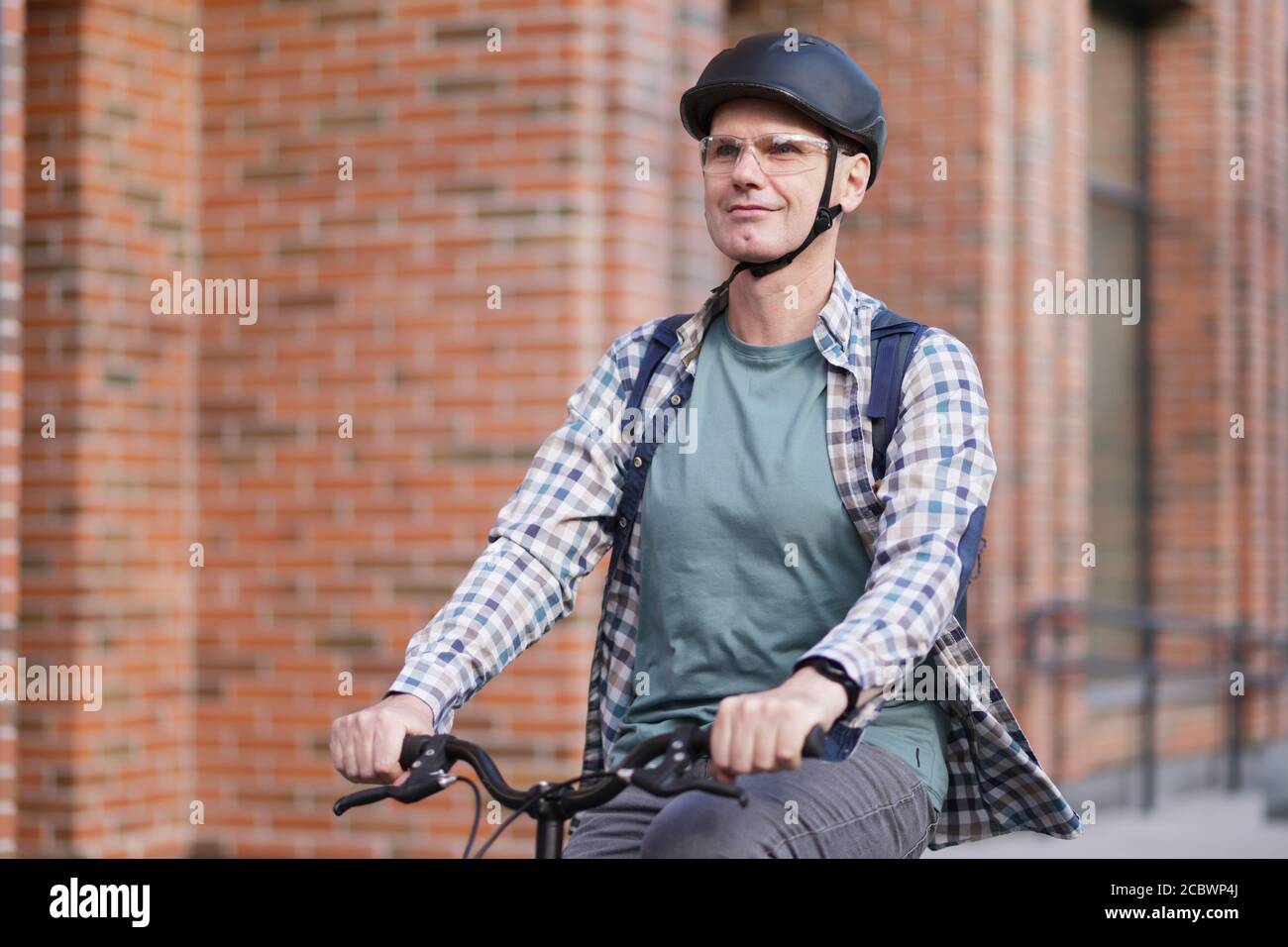 Reifer Kaukasischer Mann in einem Fahrradhelm auf seinem Fahrrad In einer Stadt Stockfoto