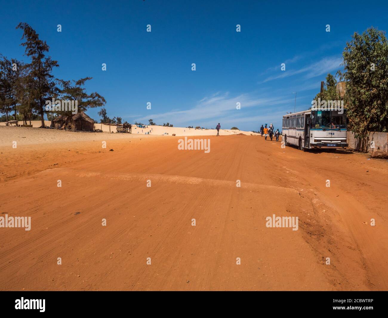 Senegal, Afrika - 02. Feb 2019: Alter Bus die Straße mit rotem und weißem Sand am Ende der vergangenen Paris-Dakar-Route Stockfoto