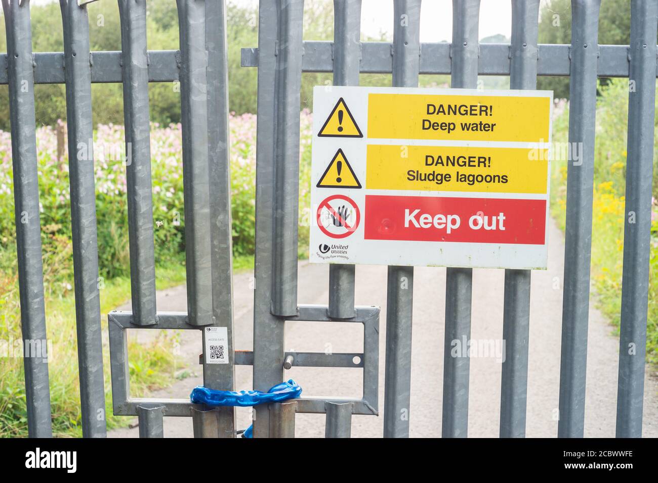 Verschlossenes Tor mit verschiedenen Gefahrenhinweisen in der Nähe einer Wasseraufbereitungsanlage von United Utilities in der Red Rock Lane, Stoneclough, England, Großbritannien Stockfoto