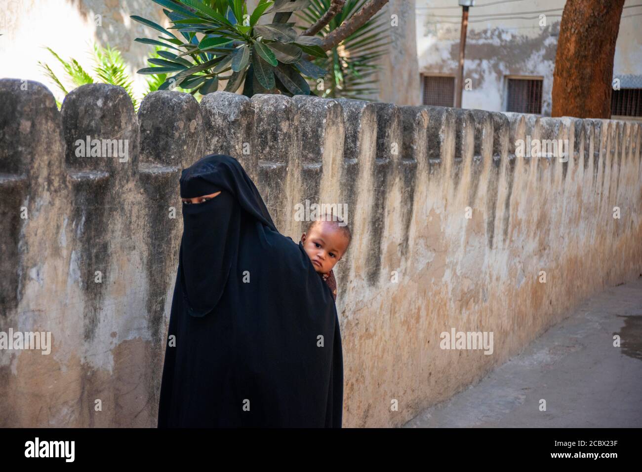 Suaheli Frau mit schwarzem Schleier und ihr Kind im strees der Stadt Lamu in Kenia Stockfoto