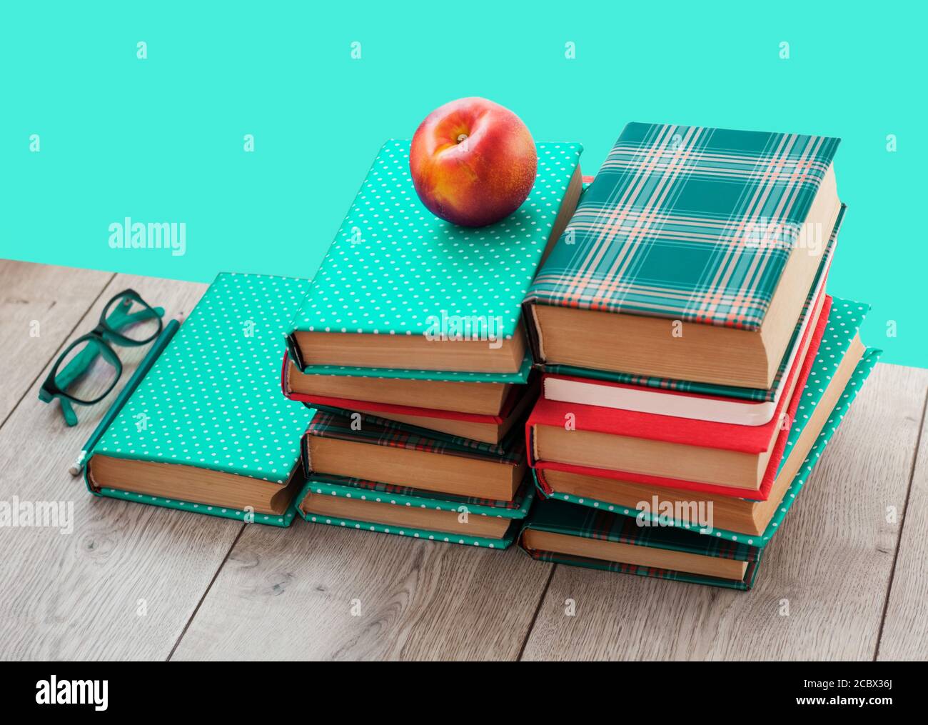 Zurück in die Schule, Stapel von Büchern in bunten Abdeckungen und Pfirsich auf Holztisch mit grünen Minze Hintergrund. Fernhausbildung.Quarantine Konzept der s Stockfoto