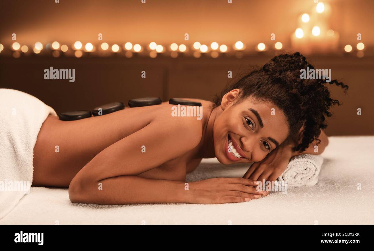 Glückliche afroamerikanische Frau genießen Hot Stone Massage im Spa Stockfoto