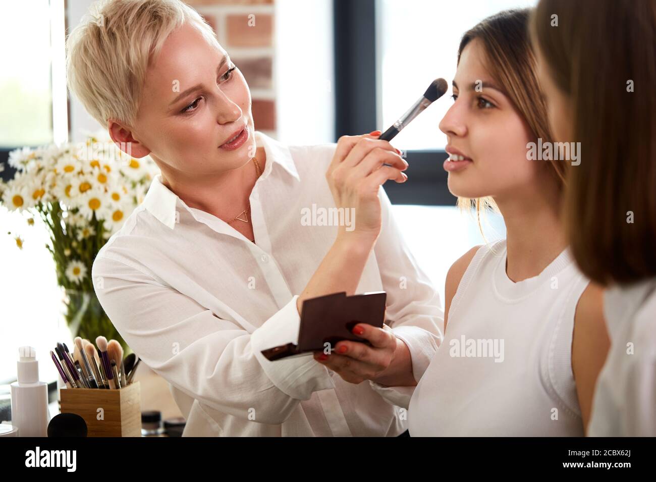 Professionelle Make-up-Lehrer, visagiste mit ihrem Schüler Mädchen Anwendung Make-up auf die Augen in der Meisterklasse in der Beauty-Schule Stockfoto