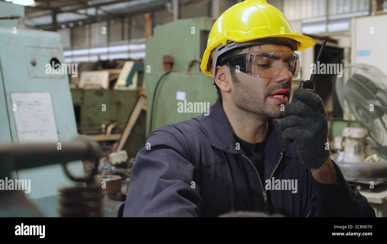 Fabrikarbeiter sprechen auf tragbarem Radio, während die Inspektion Maschinenteile Stockfoto