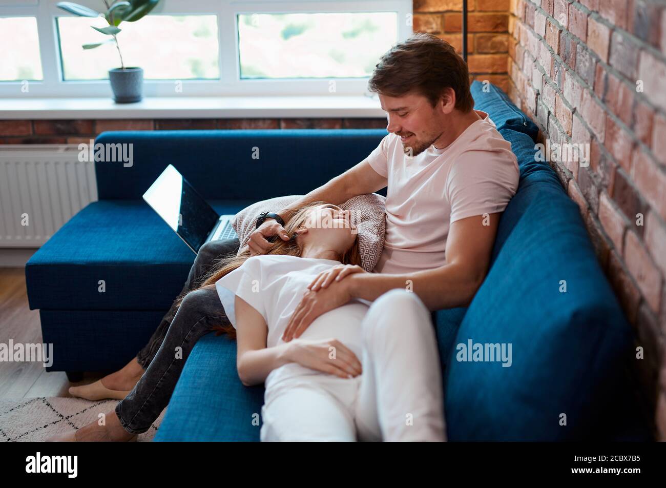 Vorsichtig schöner Mann Schlaganfall Bauch der schwangeren Frau, Ehepaar verbringen Wochenenden zu Hause, haben Ruhe. Mann und Frau in Hauskleidung, Pyjamas Stockfoto
