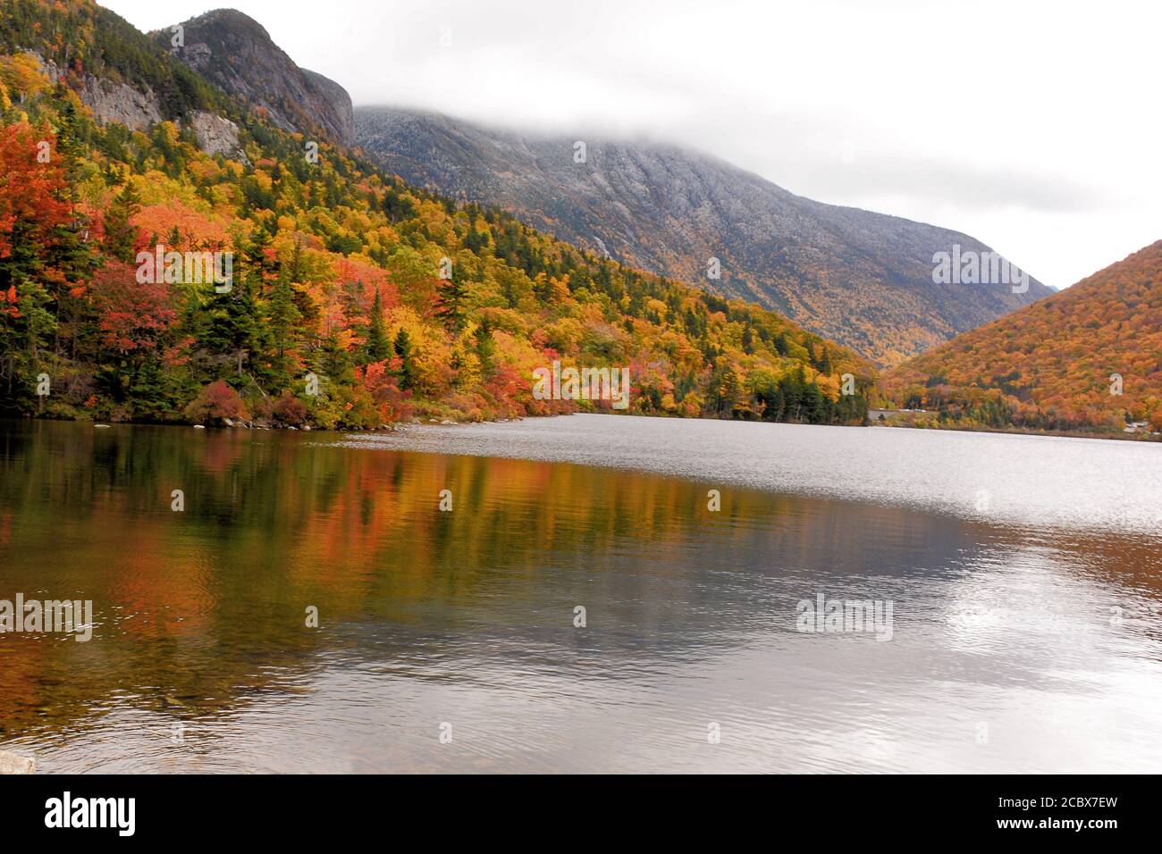 Herbst in den White Mountains von New Hampshire. Weitläufige Aussicht auf Franconia Notch und farbenfrohe Blätter vom Ufer des Echo Lake. Stauben von Schnee auf dem Berg Stockfoto