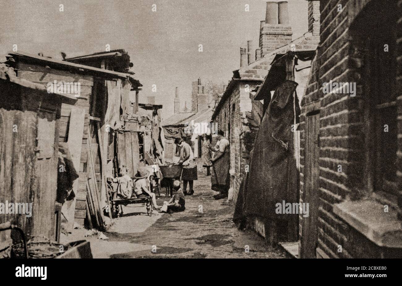 Obwohl in den 1930er Jahren viele neue Häuser gebaut wurden, gab es in britischen Städten immer noch überfüllte und ironitäre Bedingungen, eine Situation, die sich in dieser Seitengasse zeigte. Stockfoto Obwohl in den 1930er Jahren viele neue Häuser gebaut wurden, gab es in britischen Städten immer noch überfüllte und ironitäre Bedingungen, eine Situation, die sich in dieser Seitengasse zeigte. Stockfoto