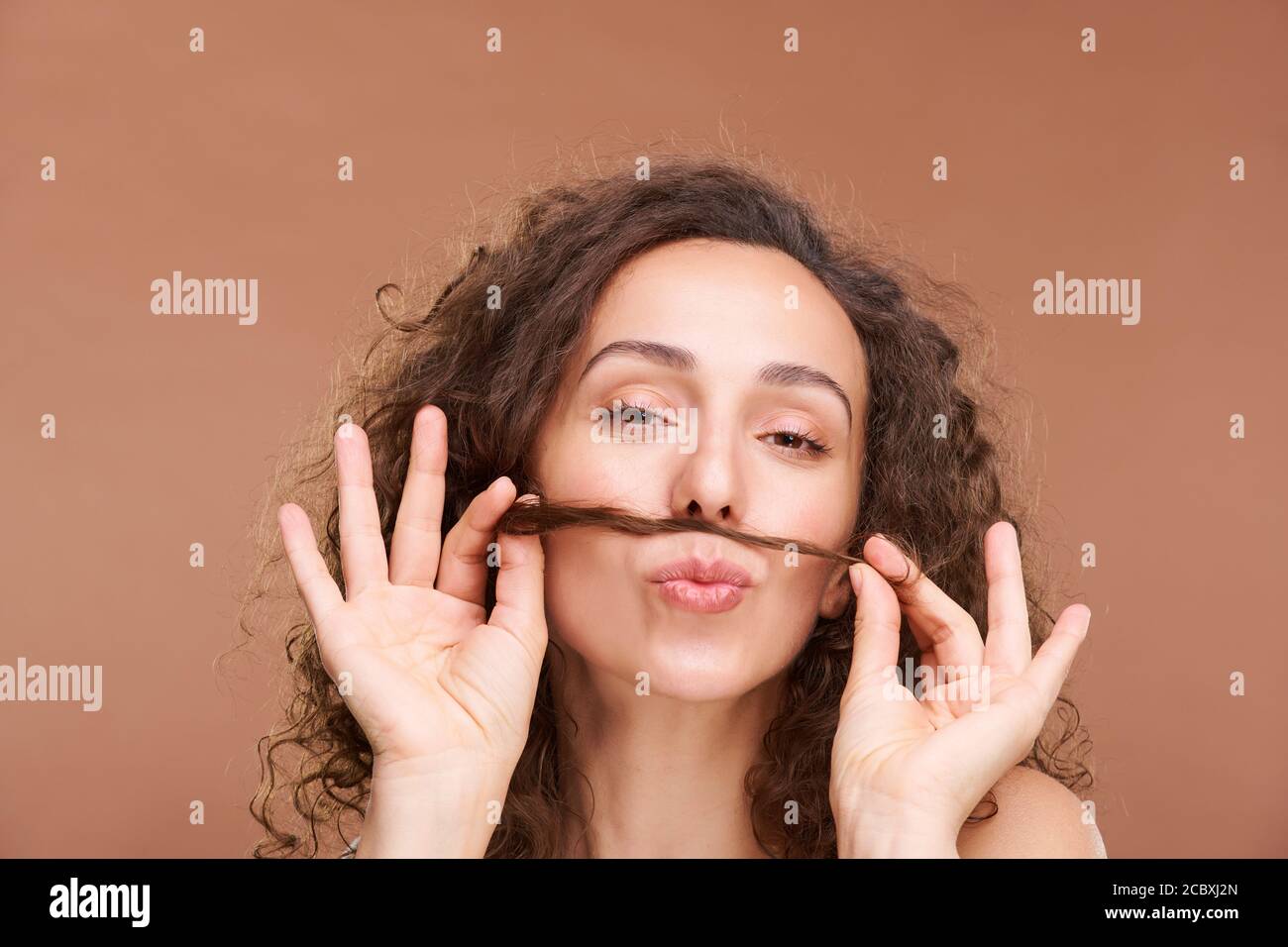 Junge lustige Brünette weiblich mit geschlossenen Augen Spaß mit Haarsträhne Stockfoto