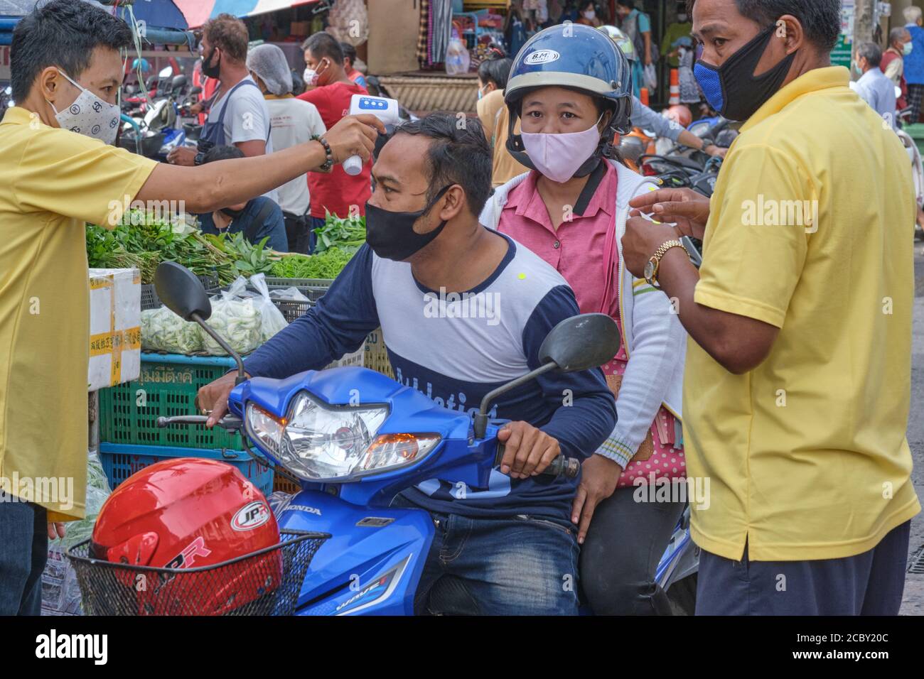 Vor dem Eintritt in einen Markt in Phuket Town, Thailand, werden im Rahmen der Covid-19 Maßnahmen die Temperaturen eines Motorradfahrpaares überprüft Stockfoto