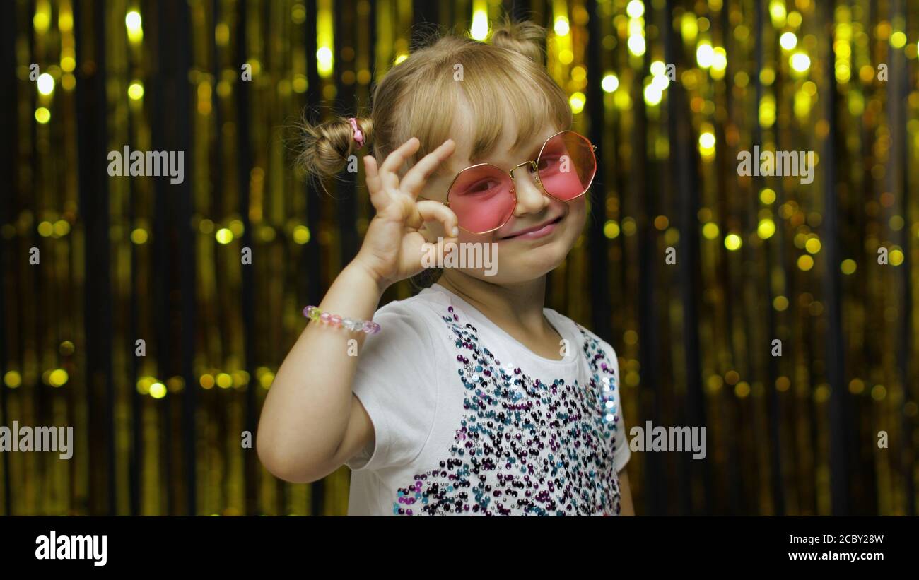 Fröhlich froh Kind zeigt ok Geste und lächelt an der Kamera mit optimistischen zufriedenen Ausdruck, okay Zeichen der Zustimmung. Wenig Spaß blonde Kind Teenager Mädchen 4-5 Jahre alt in rosa Sonnenbrille Stockfoto