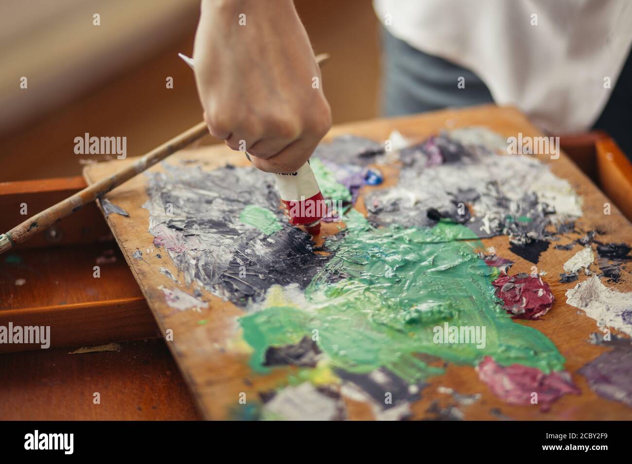 Männlicher Künstler hält Acryl-Farbtuben, mischt Farben für die Malerei auf Palette . Kunst, Kreativität, Hobby-Konzept. Nahaufnahme abgeschnitten Foto Stockfoto
