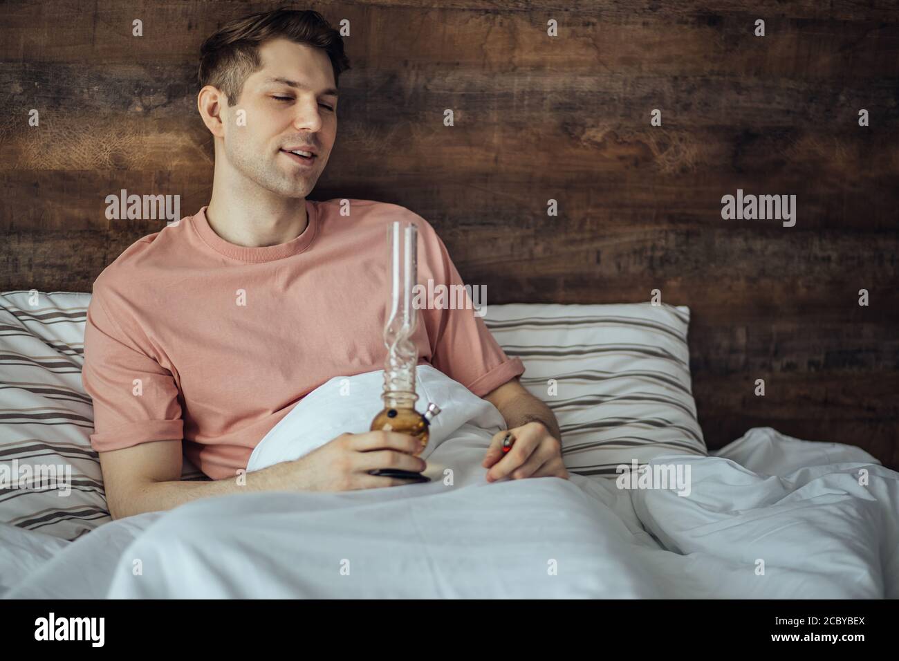 Junger Mann raucht Bong Cannabis Unkraut zu Hause. Medizinisches Marihuana, Hanfkonsum und Legalisierung des Cannabiskonzepts. Drogenbehandlung Stockfoto