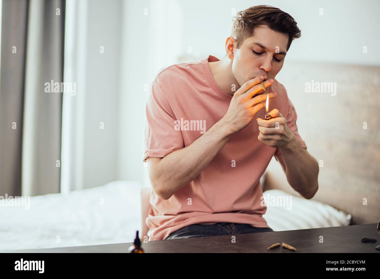 Junge kaukasische Kerl nehmen Drogen zu Hause allein. Mann führt ungesunden Lebensstil, er genießt das Rauchen Marihuana, Ganja, Cannabis. Hanf Medizin Konzept. Drogen Stockfoto