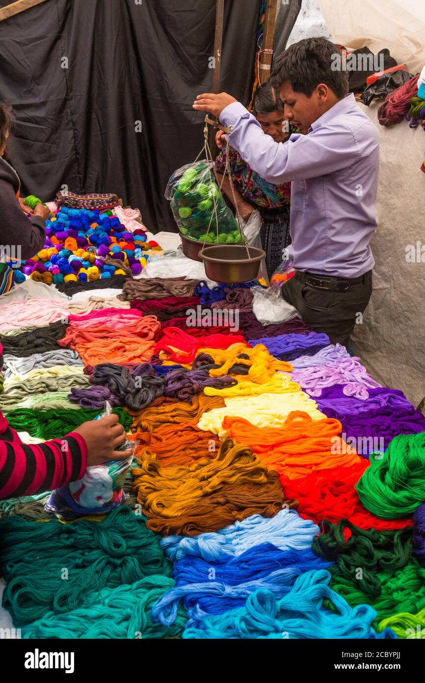 Ein Mann wiegt Garn zum Weben für den Verkauf auf dem Outdoor-Markt in Chichicastenango, Guatemala. Stockfoto