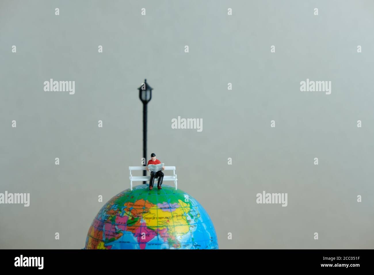 Miniatur-Bildungskonzept für das Studium im Ausland - junge Studenten lesen Über dem Globus Stockfoto