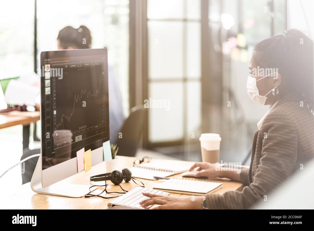 Gemischte Rasse von afrikanischen schwarzen und asiatischen Geschäftsfrau Büroangestellte Tragen Sie eine Schutzmaske, die in einem neuen normalen Büro mit arbeitet Soziale Distanz zwischen Stockfoto