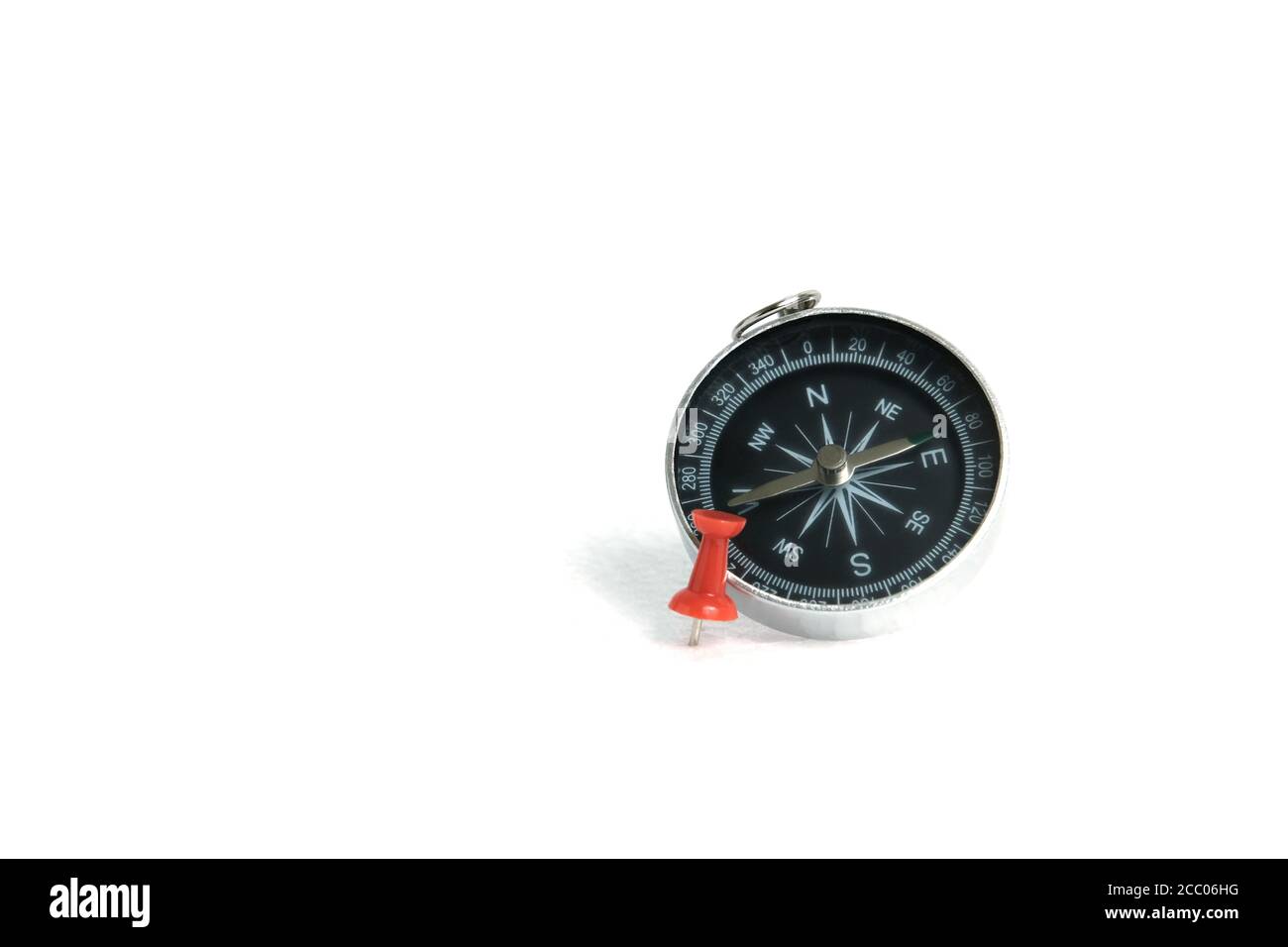 Eingebauter roter Daumennadel / Pushpin mit Kompass isoliert auf weiß Hintergrund Stockfoto