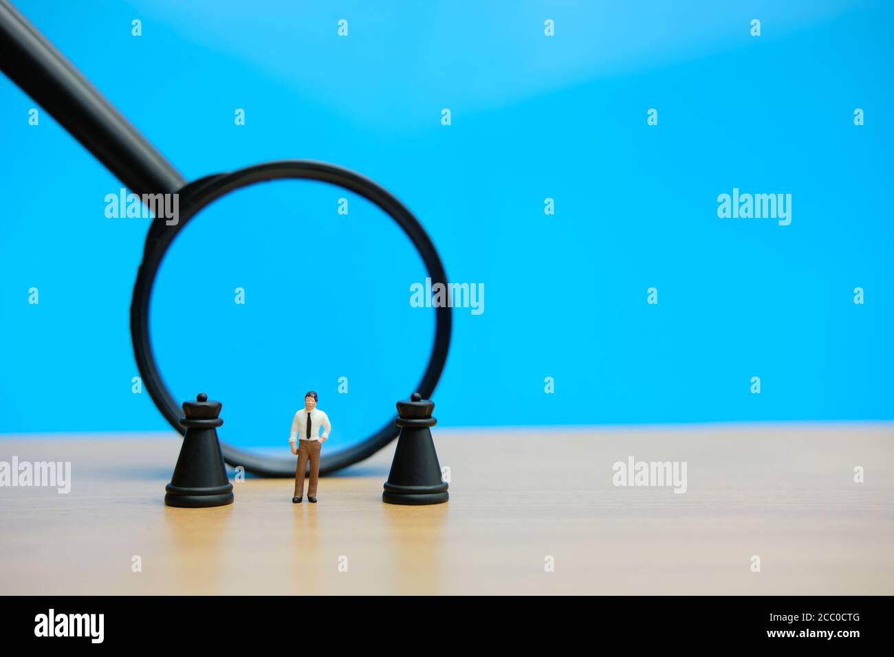 Miniatur Menschen strategisches Konzept - Geschäftsmann steht zwischen Schloss Schach Vor der Lupe gepfändet Stockfoto