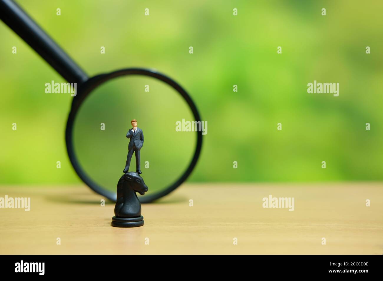 Miniatur Menschen strategisches Konzept - Geschäftsmann über einem Pferd stehen knight Schach Bauer vor der Lupe Glas Stockfoto
