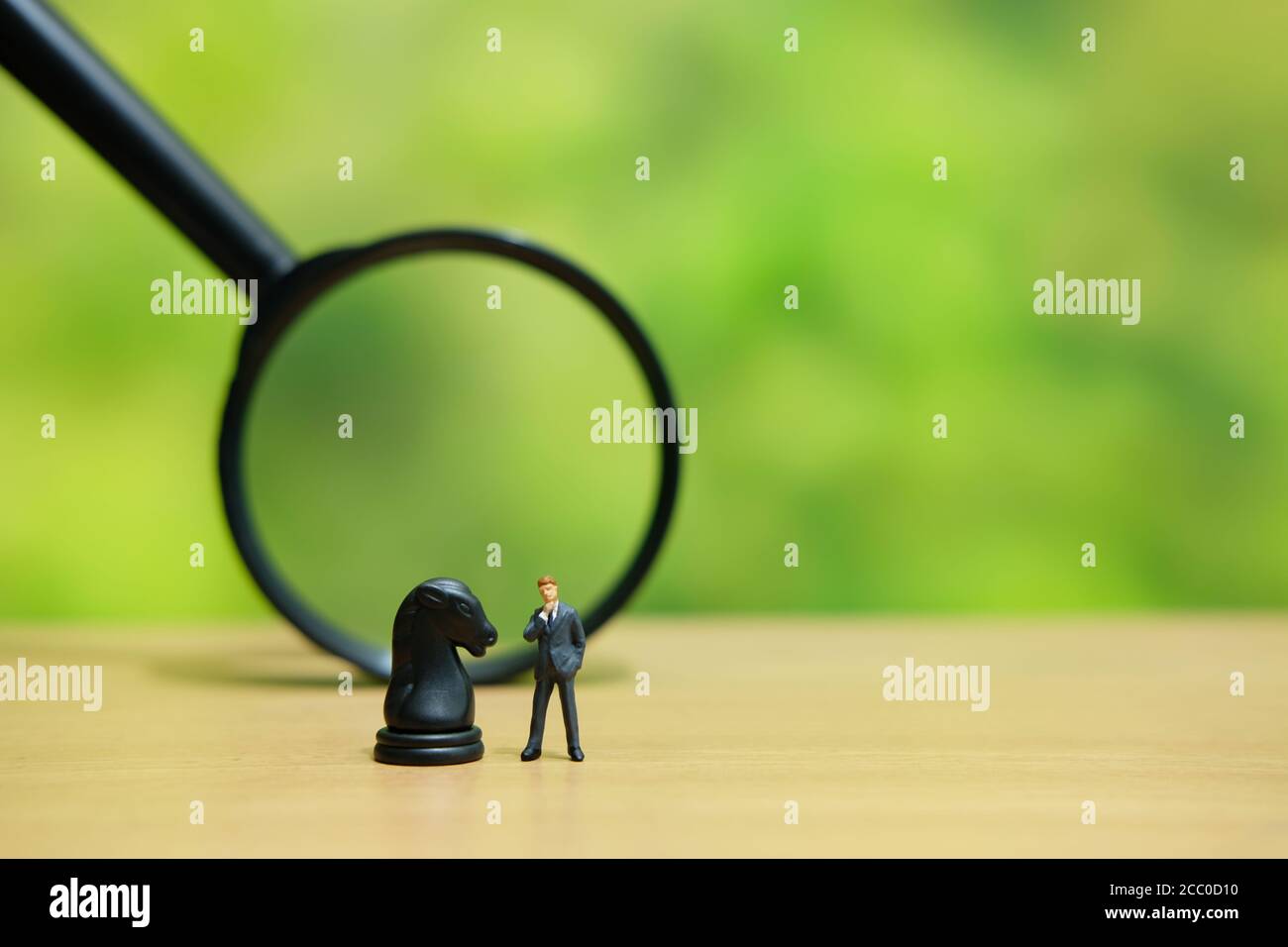 Miniatur Menschen strategisches Konzept - Geschäftsmann über einem Pferd stehen knight Schach Bauer vor der Lupe Glas Stockfoto