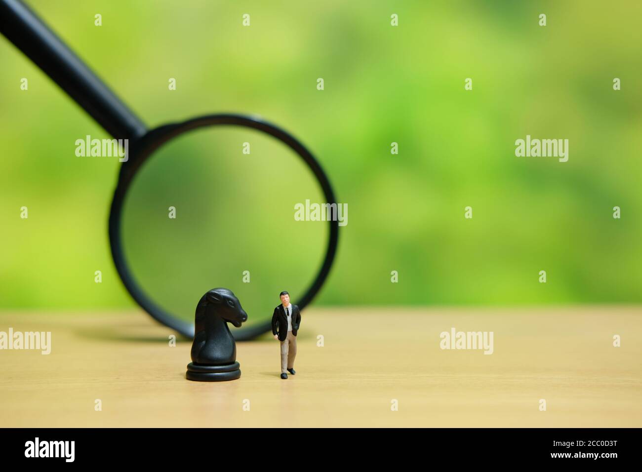 Miniatur Menschen strategisches Konzept - Geschäftsmann über einem Pferd stehen knight Schach Bauer vor der Lupe Glas Stockfoto