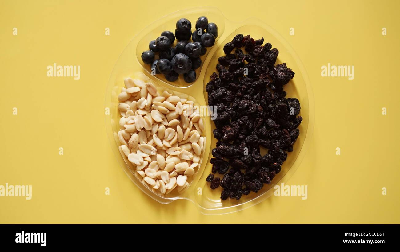 Beeren und Nüsse in runden Kunststoffbehälter für die Lagerung von Lebensmitteln - gelber Hintergrund Stockfoto