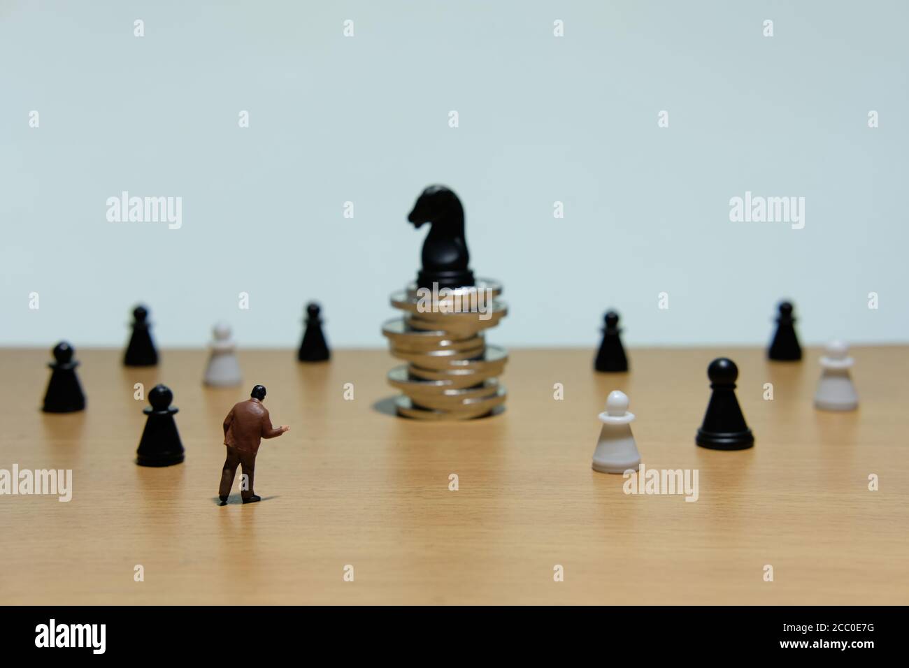 Geschäftsstrategie konzeptionelles Foto - Miniatur Geschäftsmann vor stehen Pferdeschach am Münzstapel Stockfoto