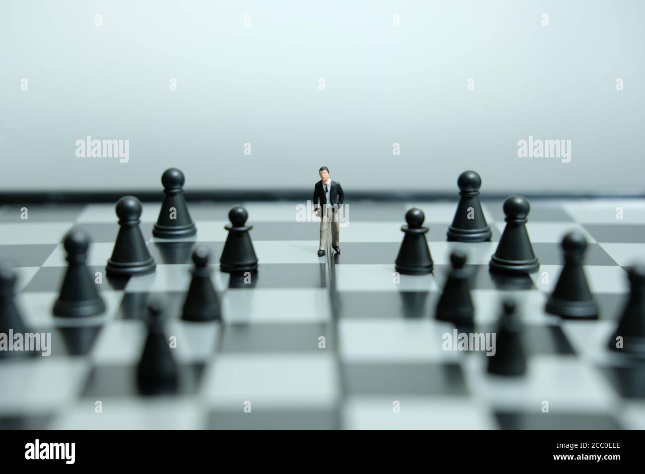 Business-Strategie konzeptuelles Foto - Miniatur des Geschäftsmannes, der vorwärts geht In der Mitte des Schachspiels auf einem Schachbrett Stockfoto
