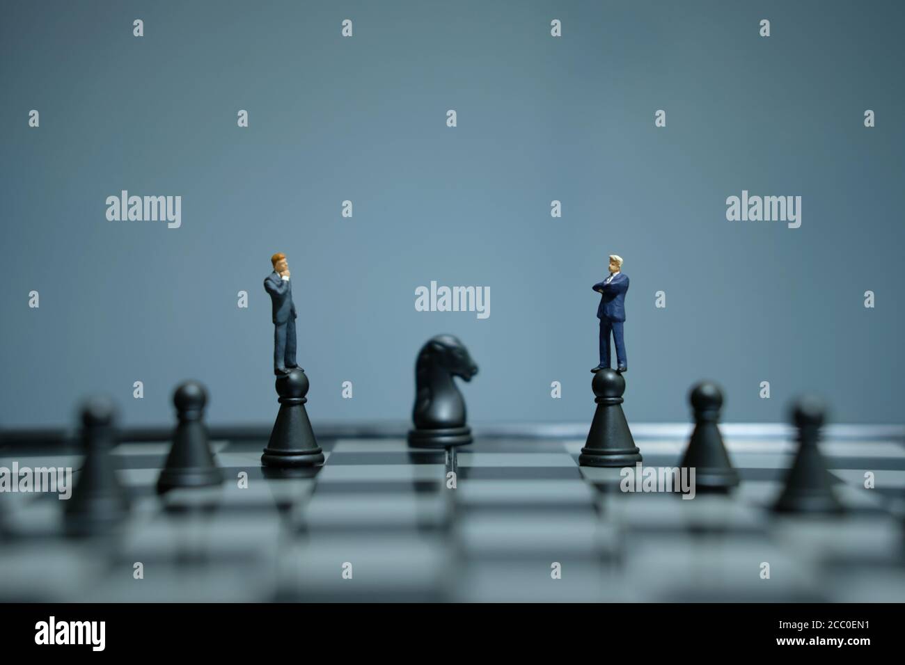 Business-Strategie konzeptuelles Foto - Miniatur Geschäftsmann über Schloss stehen Bauer auf einem Schachbrett Stockfoto