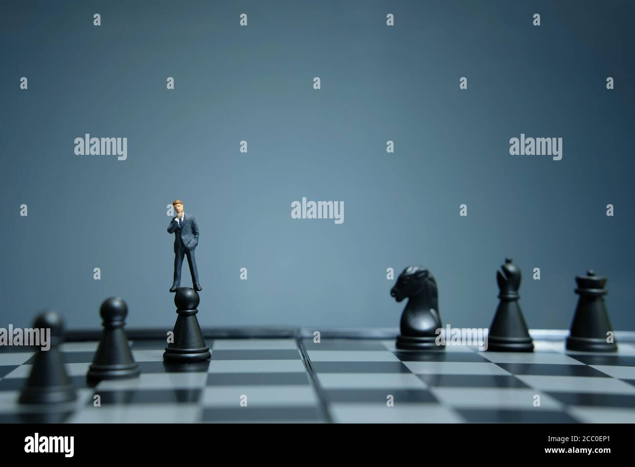 Business-Strategie konzeptuelles Foto - Miniatur Geschäftsmann über Schloss stehen Bauer auf einem Schachbrett Stockfoto