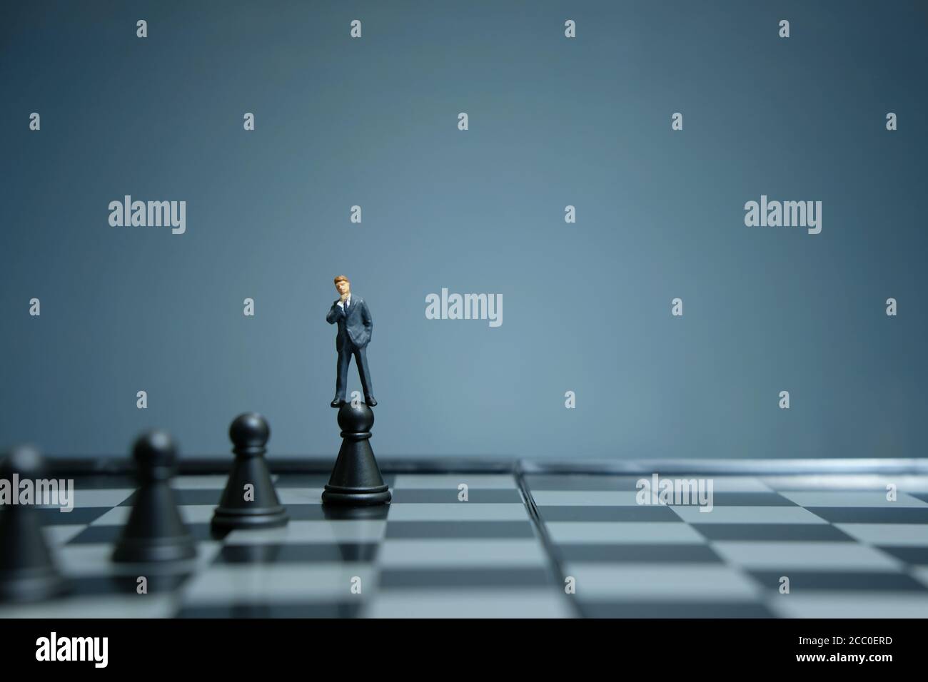 Business-Strategie konzeptuelles Foto - Miniatur Geschäftsmann über Schloss stehen Bauer auf einem Schachbrett Stockfoto