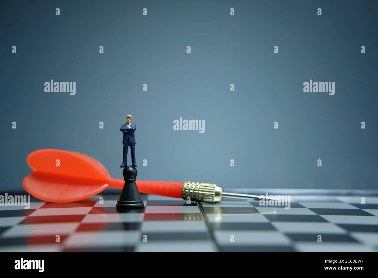 Business-Strategie konzeptuelles Foto - Miniatur Geschäftsmann über Schloss stehen Bauer auf einem Schachbrett mit rotem Pfeil Stockfoto